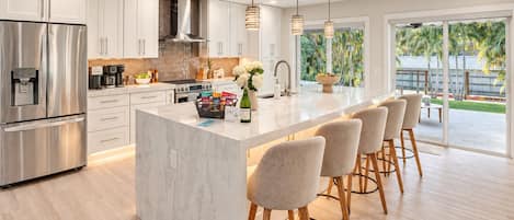 A modern kitchen with a central island, stainless steel appliances, and a view to the outdoors.