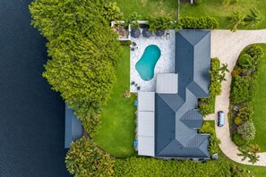 Ein Wohnhaus mit Swimmingpool, überdachter Terrasse und Bootssteg.