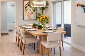 Ein Essbereich mit einem langen Holztisch, sechs Stühlen und einer Vase mit Sonnenblumen.