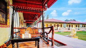 A traditional building with a red-tiled roof, a wooden bench, and a table with bottles and glasses. - Deluxehotel Banaras Kila (Pindra)