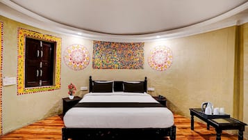 A room with a bed, a nightstand, a table with cups, and decorative wall art.