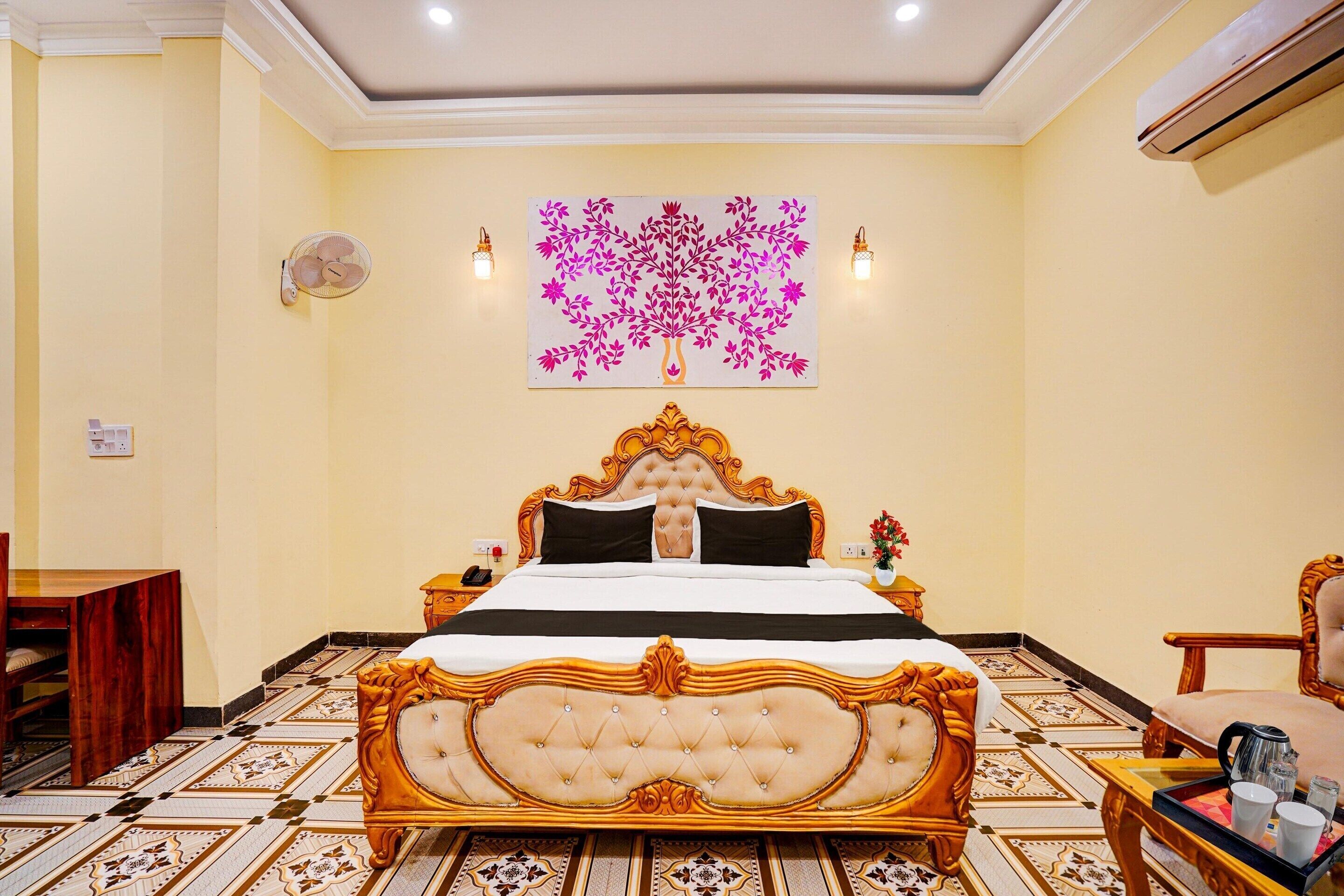 A hotel room with a large bed, a wall-mounted artwork, a bedside table, a chair, and a floor with patterned tiles.