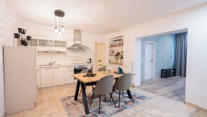 Une cuisine moderne avec des meubles blancs, une table à manger en bois et un tapis à motifs.