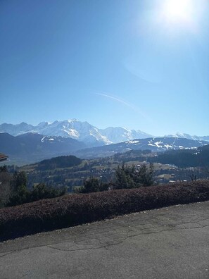 A mountainous landscape with snow-capped peaks, a clear sky, and a paved foreground. - Apartment with Mont Blanc view, terrace and garage (Cordon)