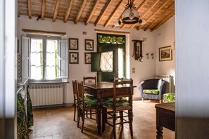 Comedor con mesa y sillas de madera, un radiador y una ventana con cortinas.