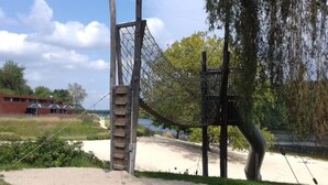 Ein Spielplatz mit Klettergerüst, Schaukeln und einem Sandbereich.