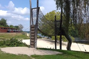 Ein Spielplatz mit Klettergerüst, Schaukeln und einem Sandbereich.