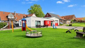 Ein Spielplatz mit Rutsche, Schaukeln und Karussell.