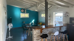 Une cuisine moderne avec un coin bar, des poutres en bois au plafond et un mur d’accent de couleur turquoise.