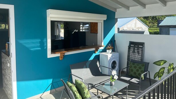 Un balcon avec un lave-linge, une fenêtre et une chaise.