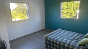 Une chambre à coucher avec un lit, deux fenêtres et un ventilateur.