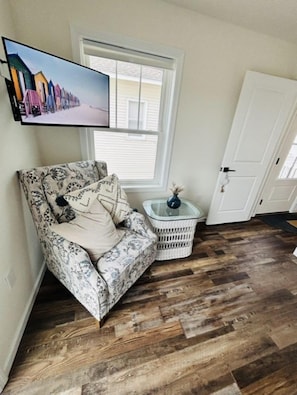 A corner room with a patterned armchair, a small side table, a television mounted on the wall, and a wooden floor. - NEW HUGE TOWNHOUSE NEAR INLET BEACH NW NIGHTLIFE RESTAURANTS SEAWALL! (North Wildwood)