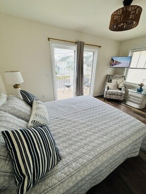 A bedroom with a bed, pillows, a chair, a TV, and a window.