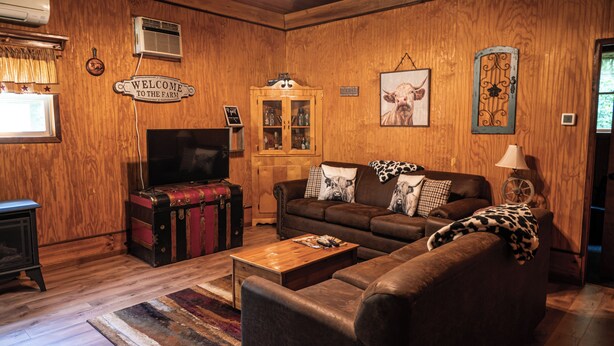 Ein gemütliches Wohnzimmer mit Ledersofa, Holzschrank und Fernseher.