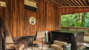 Eine Holzhütte mit Whirlpool, Korbsesseln und einem Willkommensschild.