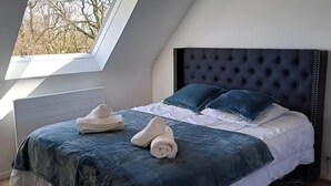 Une chambre avec un grand lit, une fenêtre et une vue sur les arbres.
