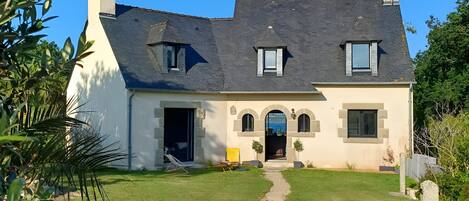 A two-story house with a stone facade, a front door, and a small front yard.