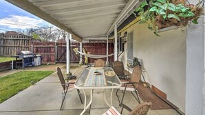 A covered patio with a table and chairs, a hammock, and a hanging plant basket. -  Adison Gold: 2BR w/ Fully Fenced Yard, Barbecue and pet friendly, Near Downtown (Carmichael)