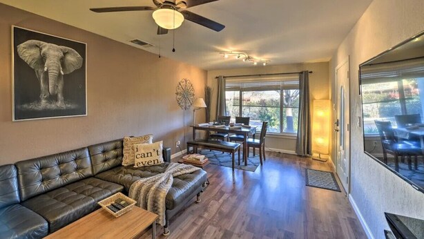 A living room with a leather sofa, a dining table, and a ceiling fan. -  Adison Gold: 2BR w/ Fully Fenced Yard, Barbecue and pet friendly, Near Downtown (Carmichael)