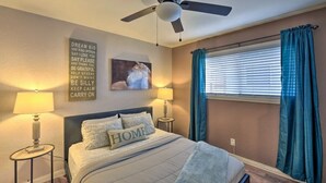 A bedroom with a bed, two bedside lamps, a ceiling fan, a window with curtains, and motivational wall art. -  Adison Gold: 2BR w/ Fully Fenced Yard, Barbecue and pet friendly, Near Downtown (Carmichael)