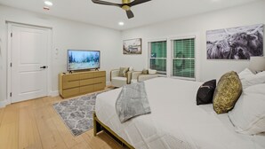 A bedroom with a bed, a TV, a ceiling fan, a dresser, a chair, and a window with blinds. - moderno farm house getaway-fire pit game room (Culpeper)