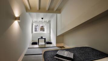 Een strak ingerichte kamer met een bed, een klein tafeltje en een raam.