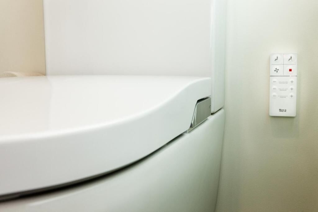 A white toilet with a control panel on the wall.
