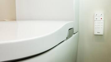 A white toilet with a control panel on the wall.