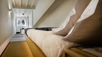 A bedroom with a bed, bedside table, and a view of the outside.