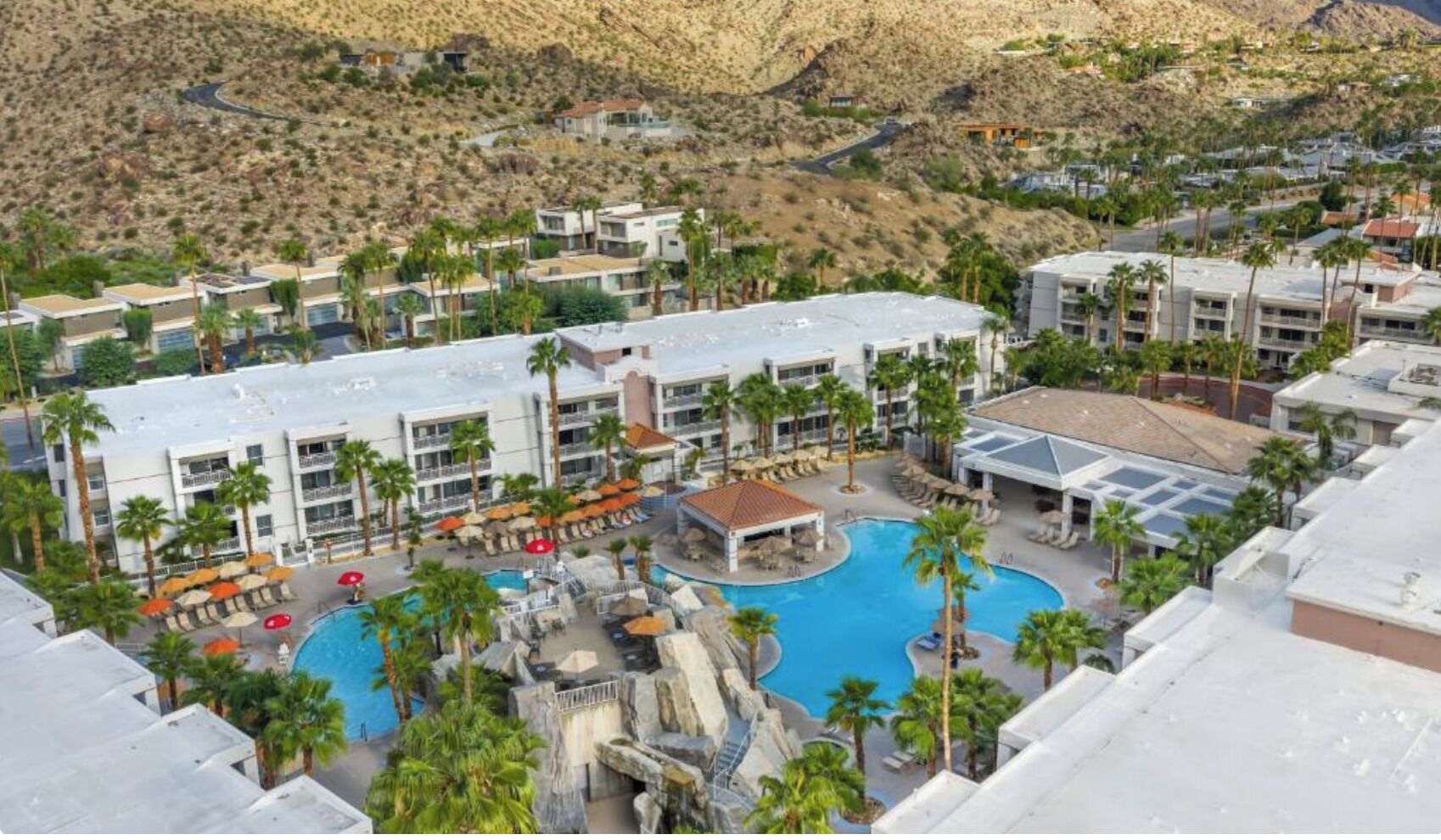 Ein Resort mit Pool, Palmen und einem Bergpanorama.