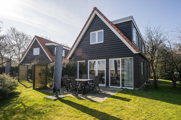 A modern house with a large patio, a dining area, and a garage. - Luxury, Peace and Space for the Whole Family (De Koog)