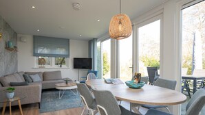 Uma sala de estar moderna com sofá, cadeiras, mesa de jantar e televisão.