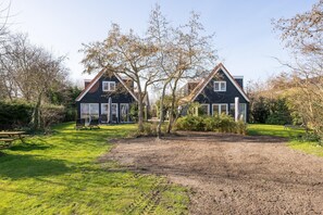 Ein zweigeschossiges Haus mit geneigtem Dach, einer Veranda und einem gepflegten Rasen.