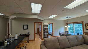 A spacious living area with a large window, a dining table, and a sofa.