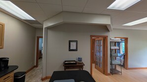 A room with a bed, a small table with a framed picture, a wooden cabinet, and a door leading to another room. - 2-Bedroom Condo in Gilford, NH come and stay at Winni Peaks and Piers Escape (Gilford)