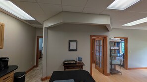A room with a bed, a small table with a framed picture, a wooden cabinet, and a door leading to another room. - 2-Bedroom Condo in Gilford, NH come and stay at Winni Peaks and Piers Escape (Gilford)