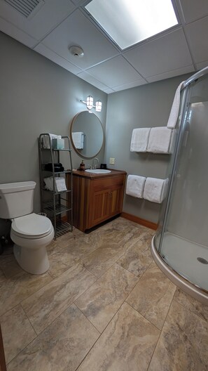 Ein Badezimmer mit Toilette, Waschbecken, Spiegel und Dusche.