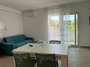 Un salon avec un canapé, une table à manger et des chaises, une télécommande et un globe en verre posé sur la table.