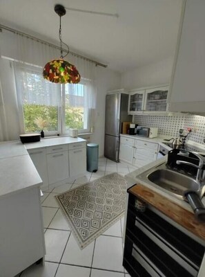A modern kitchen with white cabinets, a stainless steel refrigerator, a sink, and a patterned rug. - Spacious 3-bedroom apartment in peaceful Ginsheim-Gustavsburg with AC (Ginsheim-Gustavsburg)