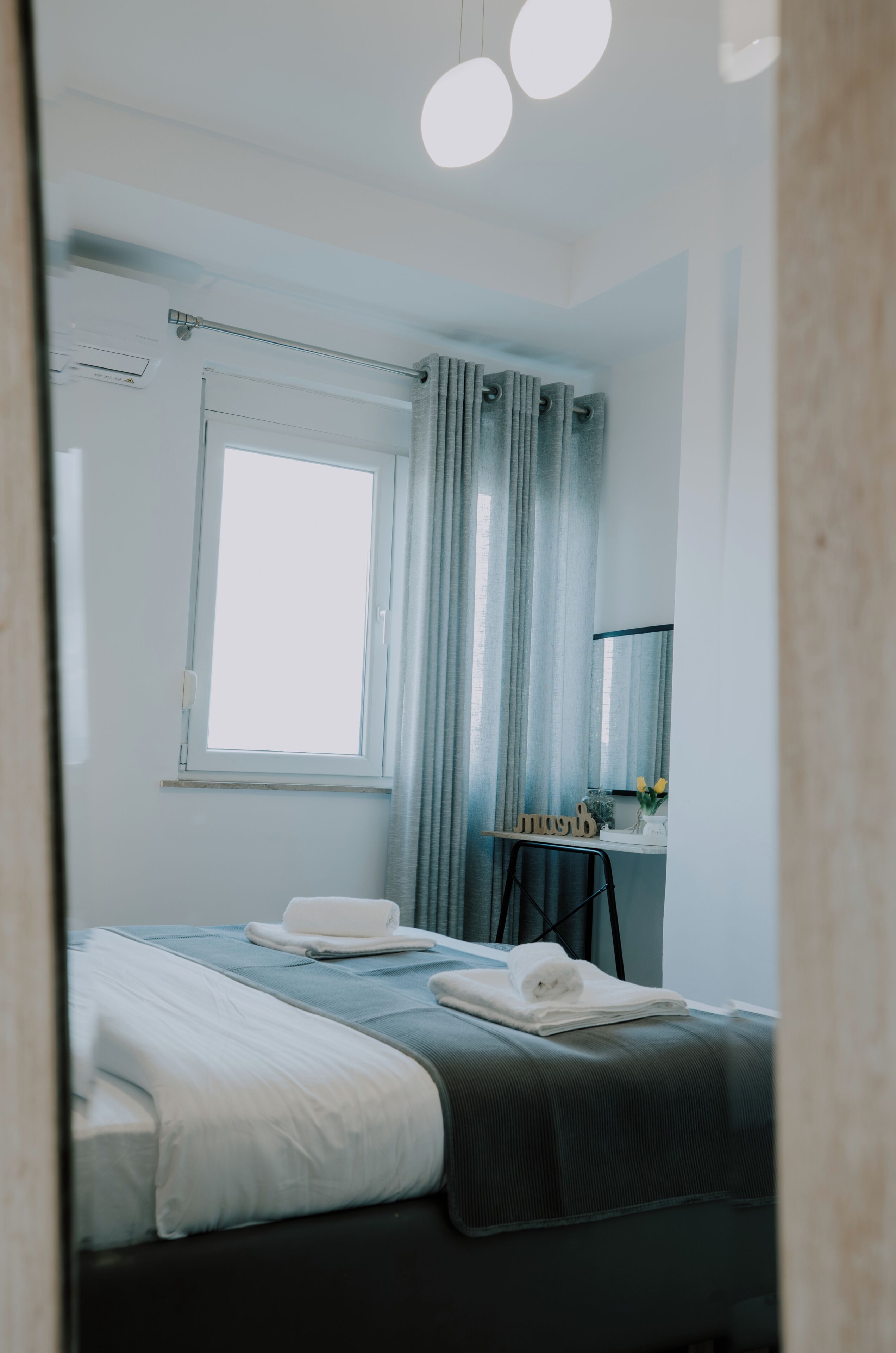 Ein Hotelzimmer mit Bett, Schreibtisch, Spiegel und einem Fenster mit Vorhängen.