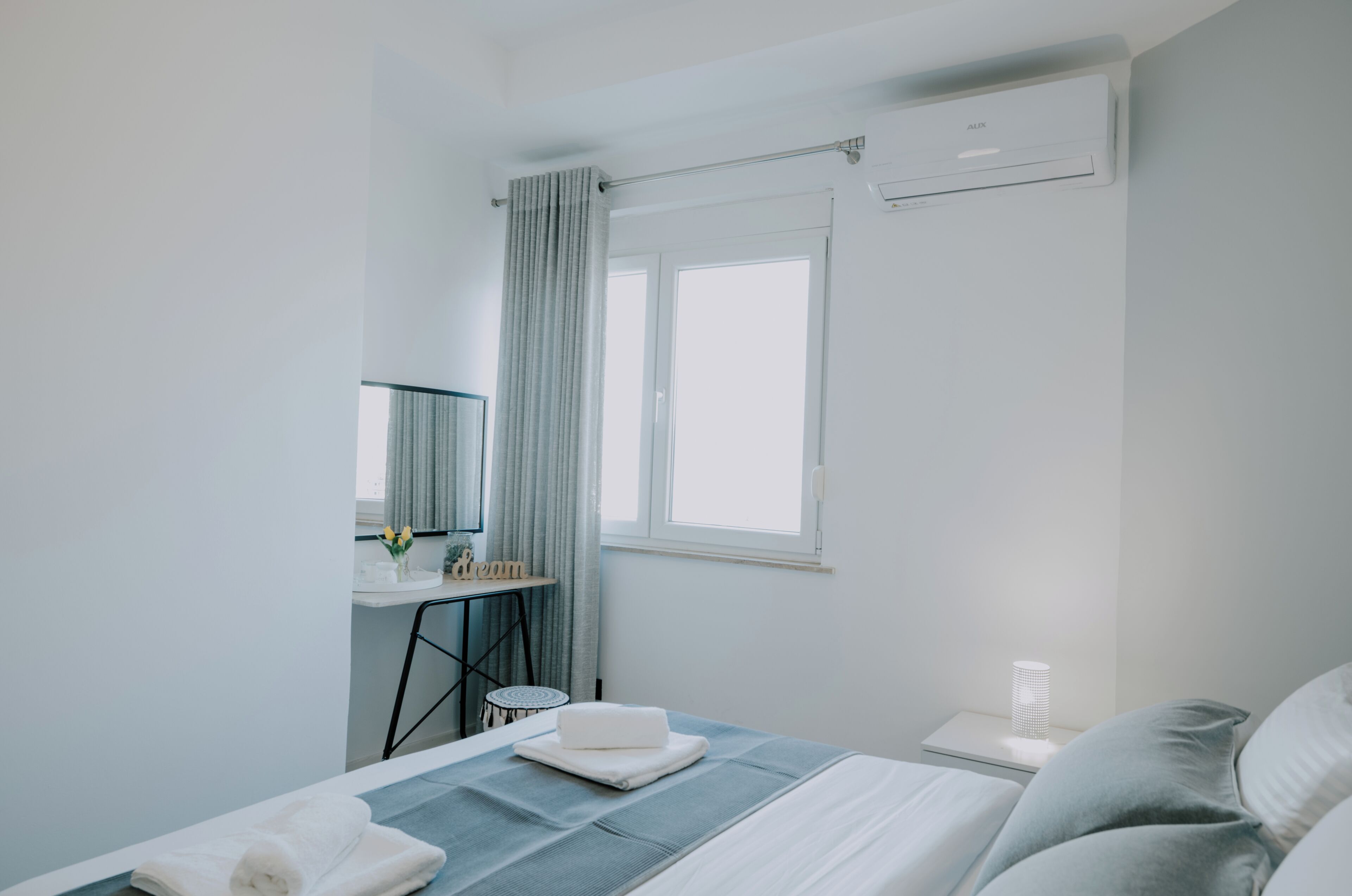 Une chambre d’hôtel moderne équipée d’un lit, d’un bureau, d’une chaise, d’une table de chevet et d’une fenêtre.