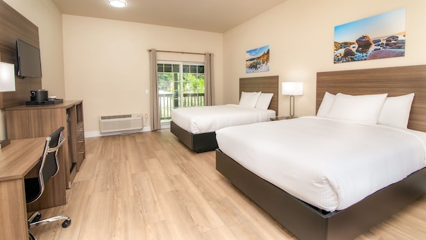A hotel room with two beds, a desk, a TV, and a window with a view of a landscape.