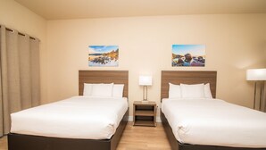A hotel room with two beds, wooden headboards, a nightstand with a lamp, and two wall-mounted paintings. - 2 Queen Bed Room- Handicap (Pollock Pines)