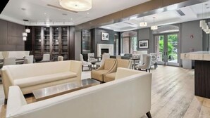 A modern hotel lobby with seating areas, a fireplace, and large windows.
