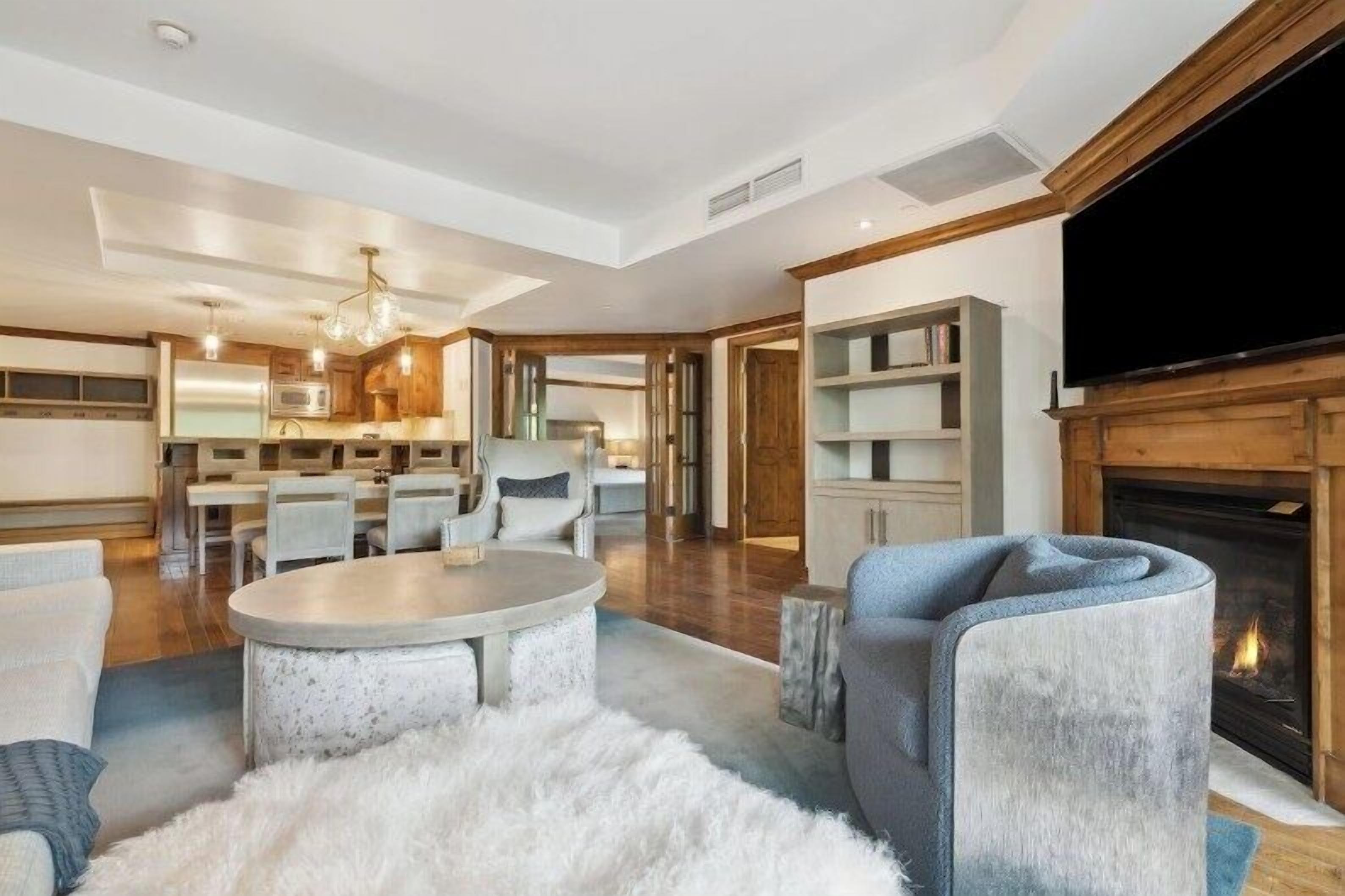 A modern living room with a fireplace, a television, and a dining area with chairs and a table.