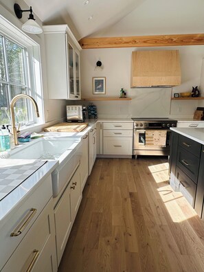 A kitchen with white cabinets, a wooden ceiling, a built-in oven, and a window. - NEW Construction: a Love Letter to Martha's Vineyard (West Tisbury)