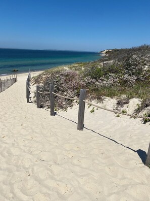 A sandy beach path leading to the ocean with wooden posts and a rope barrier. - NEW Construction: a Love Letter to Martha's Vineyard (West Tisbury)