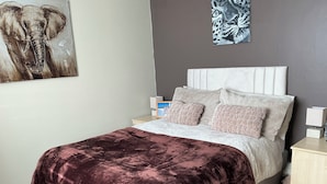 A bedroom with a bed, a nightstand, a lamp, a painting of an elephant, and a painting of a leopard. - Take a Break. Cozy Double Room. Very modern home. Full use of Bathroom,Kitchen (Leyland)