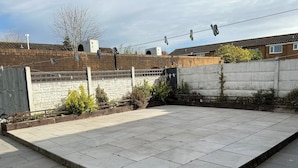 A paved outdoor area with a brick wall, a wooden fence, and a concrete wall with greenery. - Take a Break. Cozy Double Room. Very modern home. Full use of Bathroom,Kitchen (Leyland)