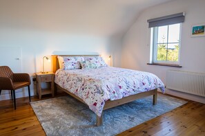 Un dormitorio con cama, mesita de noche, silla y ventana con vistas.